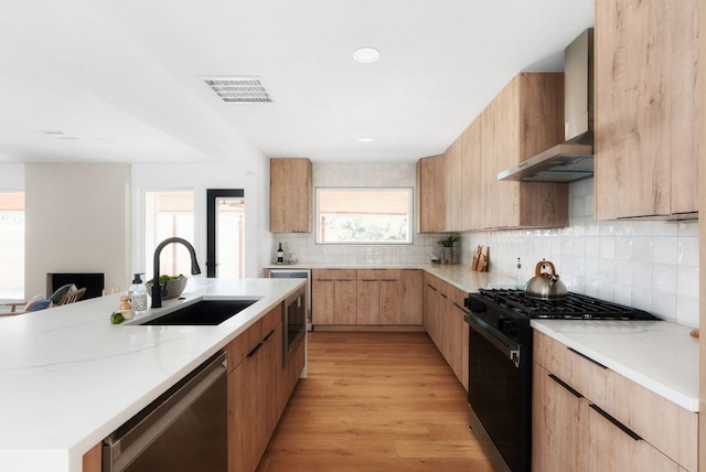 kitchen with a sink, visible vents, black gas stove, stainless steel dishwasher, and wall chimney range hood