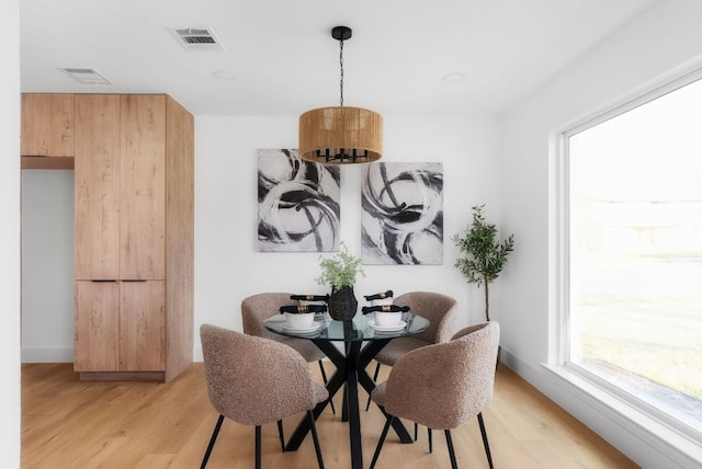 dining room with a chandelier, light wood-type flooring, and visible vents