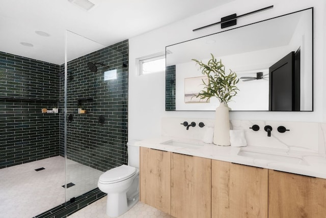 bathroom featuring double vanity, visible vents, tiled shower, toilet, and a sink