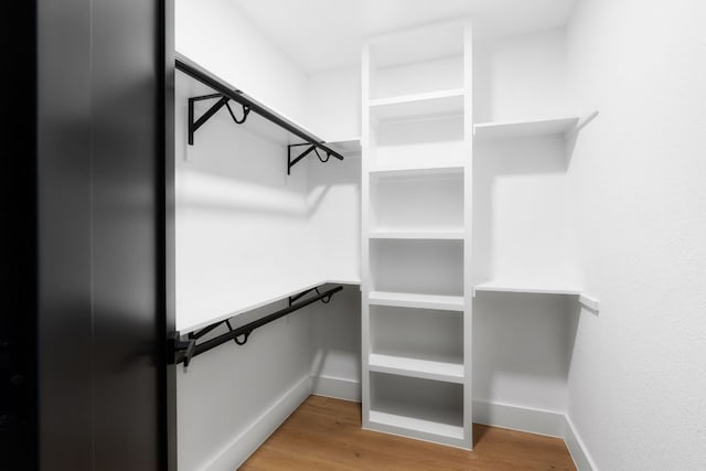 walk in closet with wood finished floors