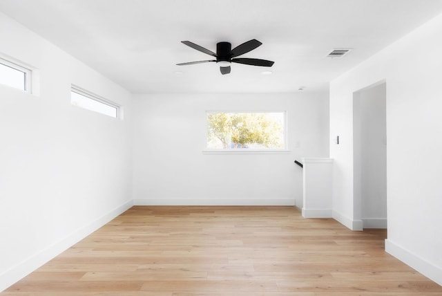 spare room with visible vents, a ceiling fan, light wood-style flooring, and baseboards