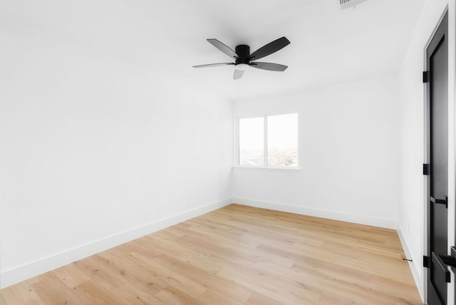 spare room featuring light wood finished floors, ceiling fan, and baseboards