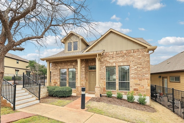 view of front of home with board and batten siding, brick siding, fence, and a shingled roof