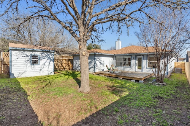rear view of property featuring a chimney, central AC unit, a fenced backyard, a yard, and a wooden deck