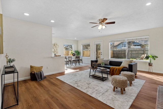 living area featuring a textured ceiling, recessed lighting, wood finished floors, a ceiling fan, and baseboards