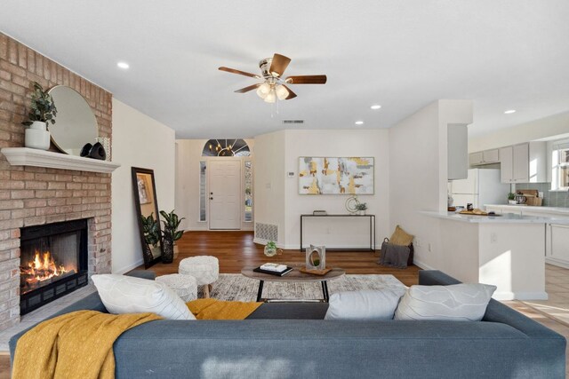 living room featuring light wood finished floors, visible vents, a fireplace, and ceiling fan