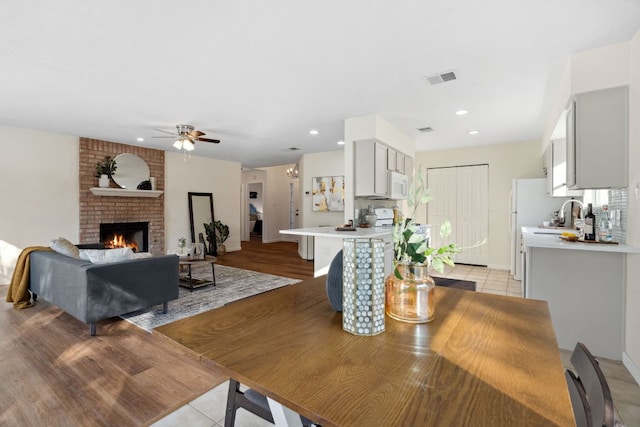 dining space with recessed lighting, visible vents, a ceiling fan, light tile patterned flooring, and a brick fireplace