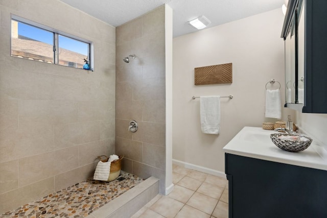 full bath with a tile shower, vanity, and tile patterned floors