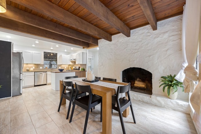 dining room with light tile patterned floors, recessed lighting, wood ceiling, a large fireplace, and beamed ceiling