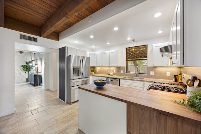 kitchen with visible vents, wood counters, a sink, stainless steel appliances, and backsplash