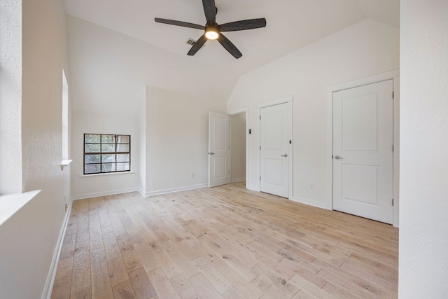 unfurnished bedroom featuring lofted ceiling, light wood-style flooring, and baseboards