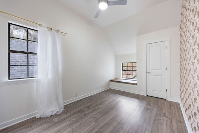 empty room with a ceiling fan, baseboards, vaulted ceiling, and wood finished floors