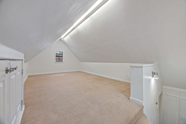 additional living space featuring vaulted ceiling and light colored carpet