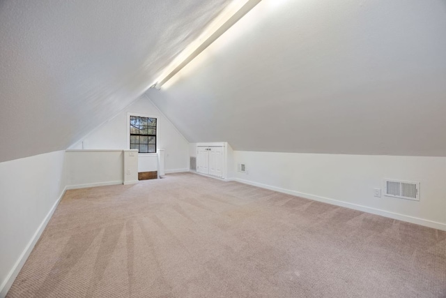 bonus room with light carpet, lofted ceiling, visible vents, and baseboards