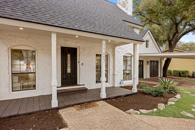 entrance to property with a porch, roof with shingles, a chimney, and stucco siding