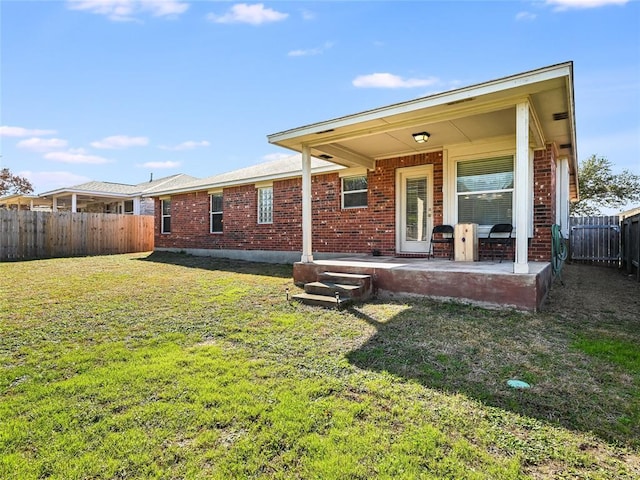 back of property with a patio, brick siding, a lawn, and a fenced backyard