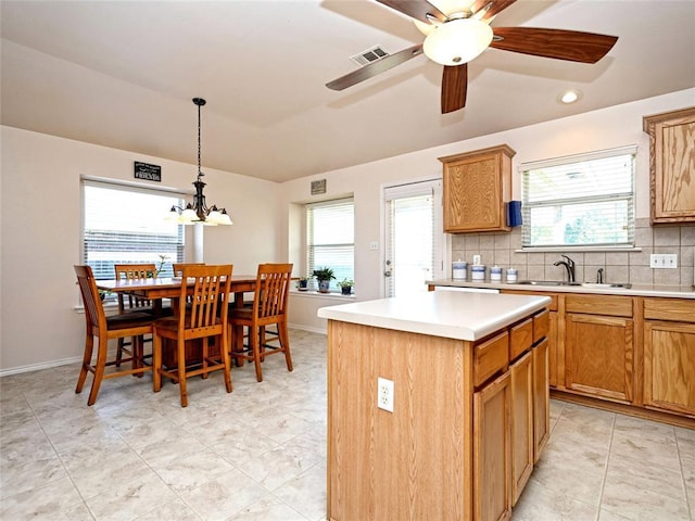 kitchen with plenty of natural light, a kitchen island, backsplash, and a sink