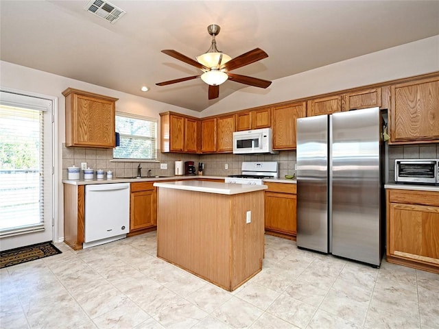 kitchen with brown cabinets, light countertops, visible vents, a sink, and white appliances