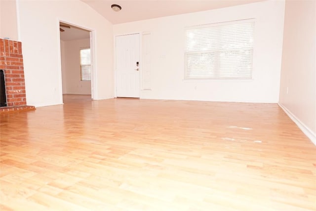 unfurnished living room featuring a brick fireplace, light wood-style flooring, and plenty of natural light