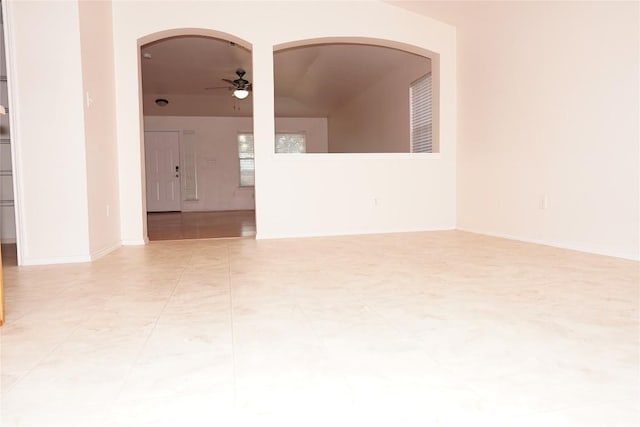 spare room with ceiling fan, arched walkways, and baseboards