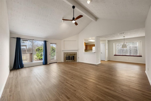 unfurnished living room with beam ceiling, a fireplace, a textured ceiling, and wood finished floors