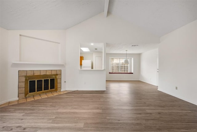 unfurnished living room featuring baseboards, a tiled fireplace, wood finished floors, high vaulted ceiling, and beam ceiling