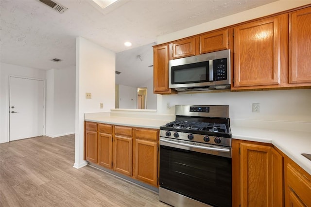 kitchen with stainless steel appliances, light countertops, brown cabinetry, and visible vents