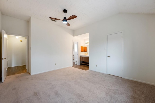 unfurnished bedroom featuring vaulted ceiling, carpet flooring, visible vents, and connected bathroom