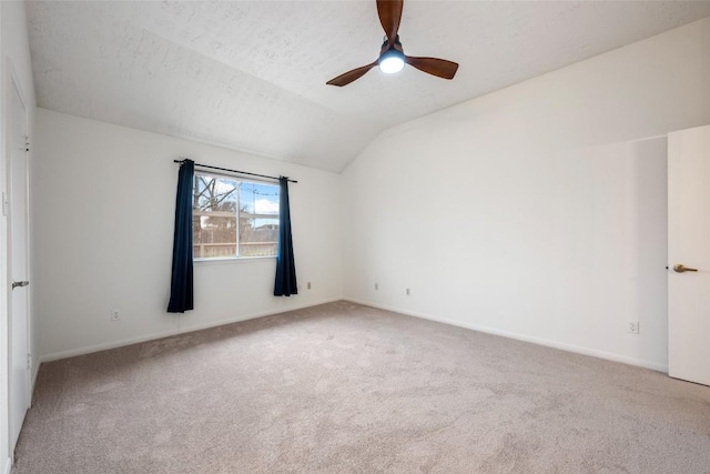 carpeted spare room with a ceiling fan, vaulted ceiling, a textured ceiling, and baseboards