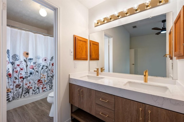 bathroom with toilet, double vanity, a sink, and wood finished floors