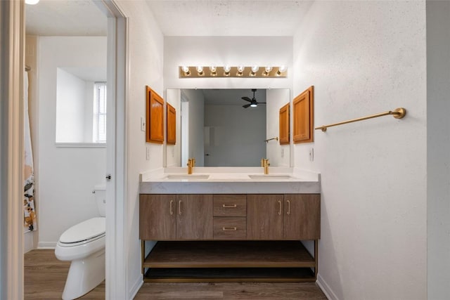 full bathroom with double vanity, wood finished floors, a sink, and toilet