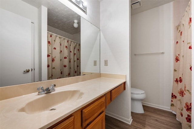 bathroom with visible vents, toilet, vanity, wood finished floors, and baseboards