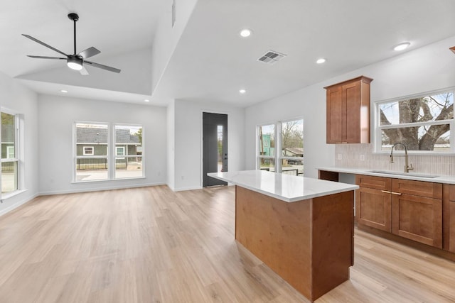 kitchen featuring a sink, visible vents, light wood-style floors, open floor plan, and backsplash