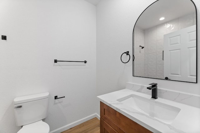 bathroom featuring wood finished floors, vanity, toilet, and baseboards