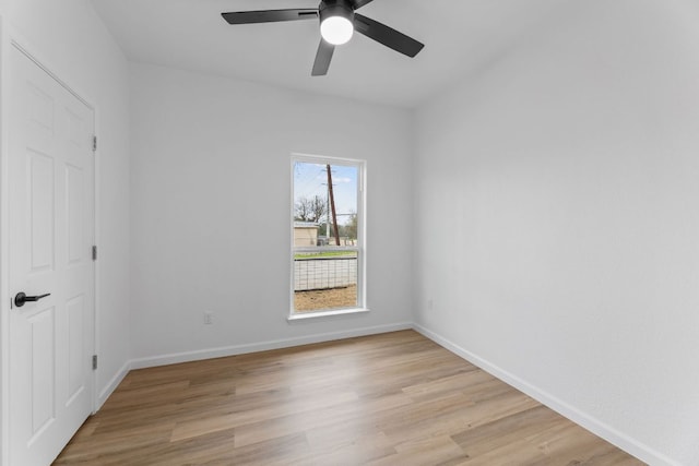 empty room featuring a ceiling fan, light wood-type flooring, and baseboards