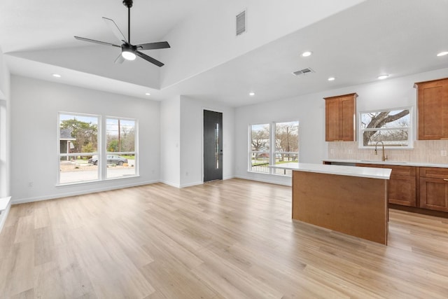 unfurnished living room with light wood-style floors, visible vents, and a sink