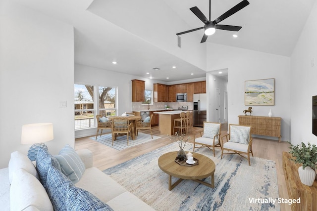 living room with light wood-style flooring, high vaulted ceiling, a ceiling fan, and recessed lighting