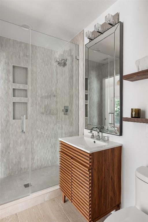 bathroom featuring a shower stall, toilet, and vanity