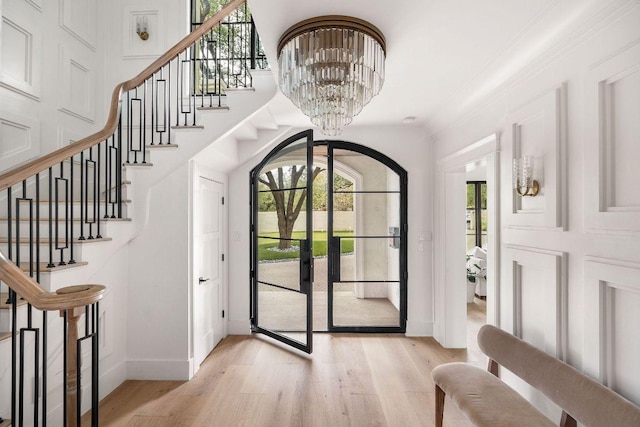 foyer with light wood-style floors, a notable chandelier, stairway, and baseboards