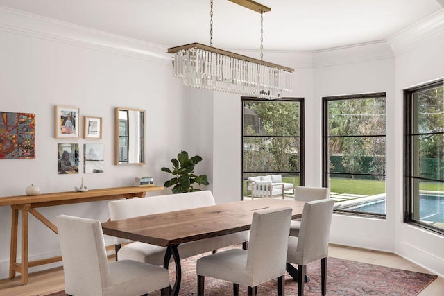 dining room featuring baseboards, ornamental molding, light wood-style flooring, and an inviting chandelier