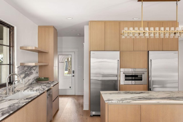 kitchen with appliances with stainless steel finishes, a sink, light stone counters, and open shelves