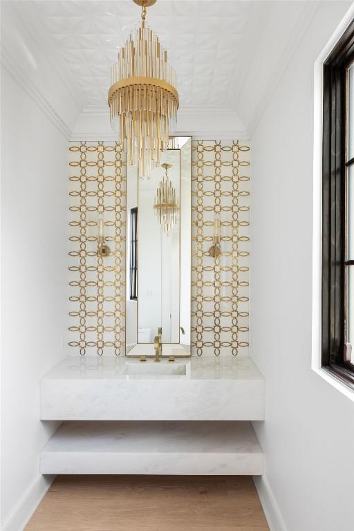 interior space with baseboards, an inviting chandelier, wood finished floors, and crown molding