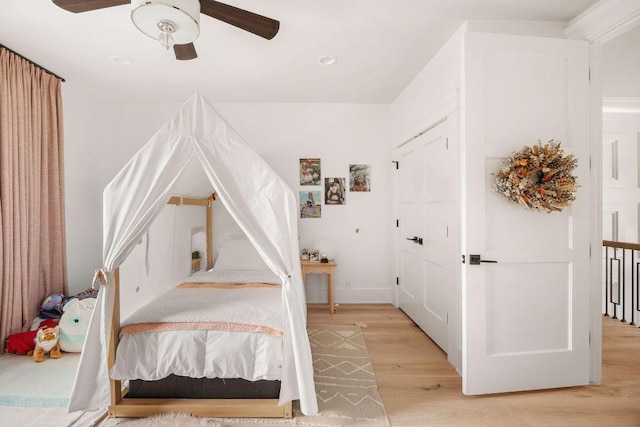 bedroom featuring light wood-style floors, baseboards, and a ceiling fan