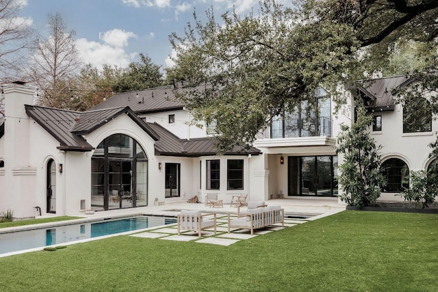 rear view of house with metal roof, a patio, a standing seam roof, and a lawn