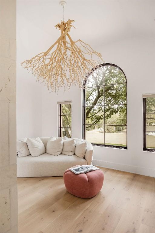 sitting room featuring wood finished floors, a towering ceiling, and baseboards