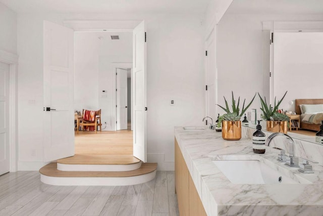 bathroom with wood finished floors, a sink, and visible vents