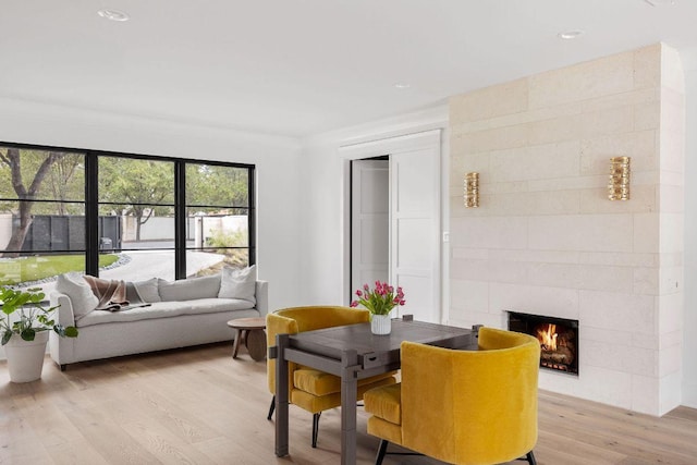 dining space featuring light wood finished floors, a tiled fireplace, and recessed lighting