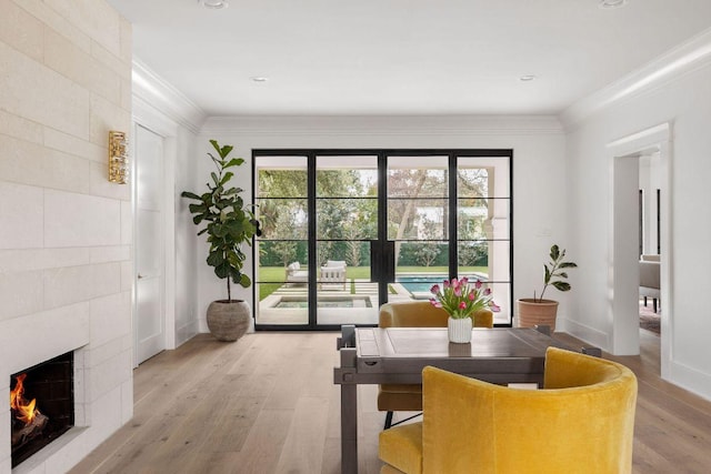 interior space featuring ornamental molding, baseboards, light wood-style flooring, and a tiled fireplace