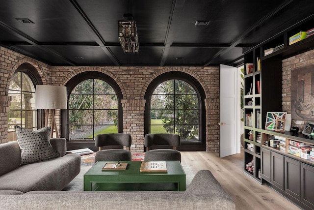 interior space featuring visible vents, brick wall, wood finished floors, coffered ceiling, and beamed ceiling