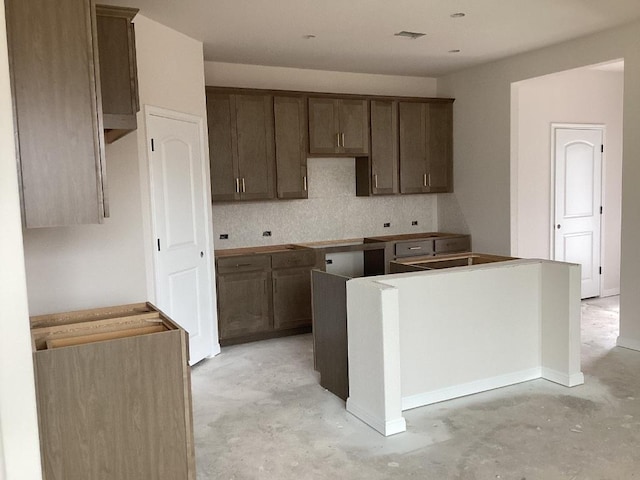 kitchen with concrete flooring, a center island, visible vents, and backsplash